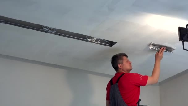 Человек-штукатурщик шлёпает потолок шпатлевкой. Новые отделочные работы — стоковое видео