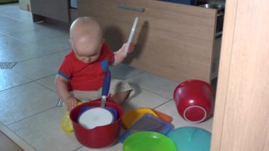 Mutfak zeminüzerinde kase ile oynayan yaramaz çocuk