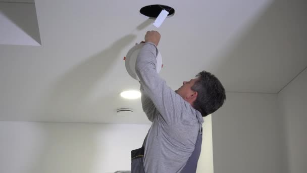 熟練した電気技師の男は、導かれた光パネルにワイヤを接続し、天井にマウント — ストック動画