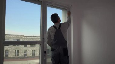 Pencere yakınında küçük el rulo boyama duvar kenarları ile Handyman