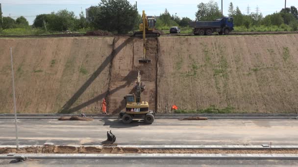 新しい高速道路道路の近くに地球レベリングマシン掘削機レベルの急速な丘の斜面 — ストック動画