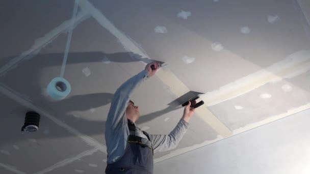Obrero cualificado hombre spackling techo de yeso drywall con paleta — Vídeos de Stock