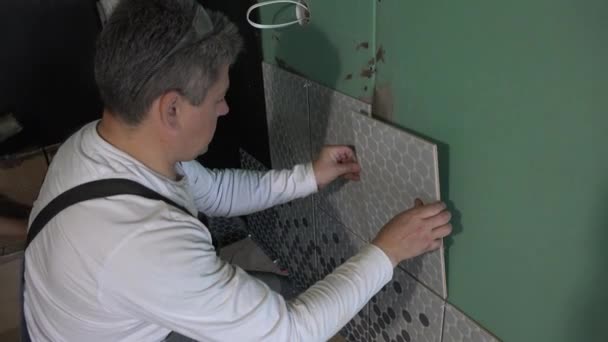 Muž, který používá keramické dlaždice na zeď koupelny. Ruční snímek — Stock video