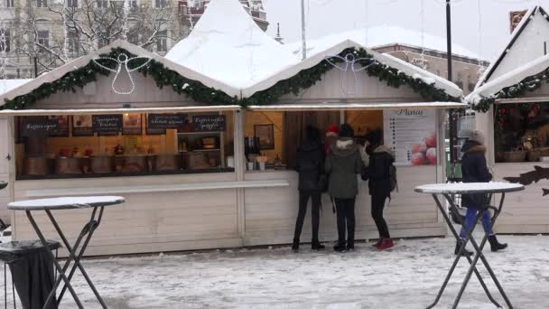 年轻姑娘们从圣诞市集摊贩那里买甜甜圈。 下雪了 — 图库视频影像
