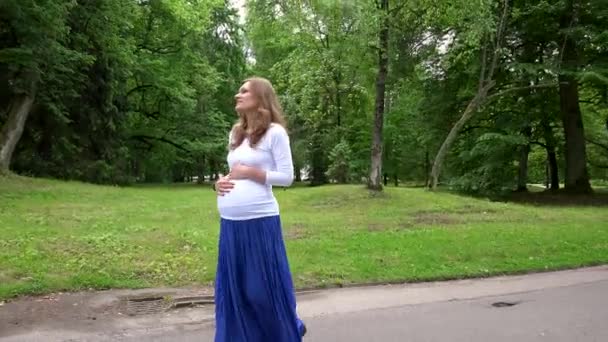 Pregnant woman expectant mother walk through park. — Stock Video