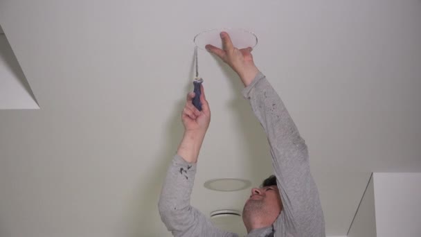 Electrician with handsaw saw hole in gypsum ceiling for lighting installation — Stock Video