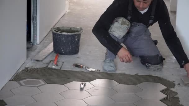 Handyman posa piastrelle esagonali trend sul pavimento in corridoio — Video Stock