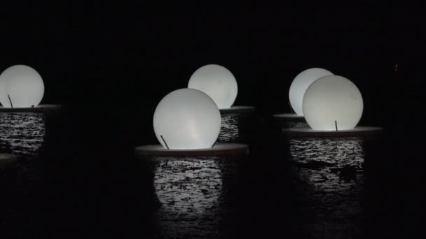 Lâmpadas lanternas redondas instaladas na superfície do lago e reflexos de luz.4K — Vídeo de Stock