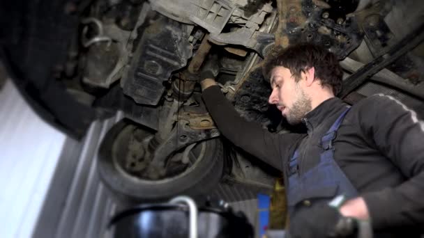 Schmutzige Automechaniker schrauben verschlissenen Ölfilter unter angehobenem Auto während der Wartung ab — Stockvideo