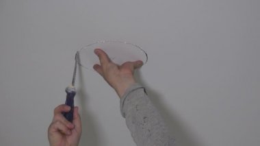 Alçıpan tavanında delik açan el testereli bir işçi.