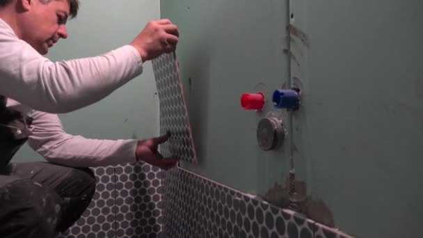 Skilled worker install lay tiles on bathroom wall — Stock Video