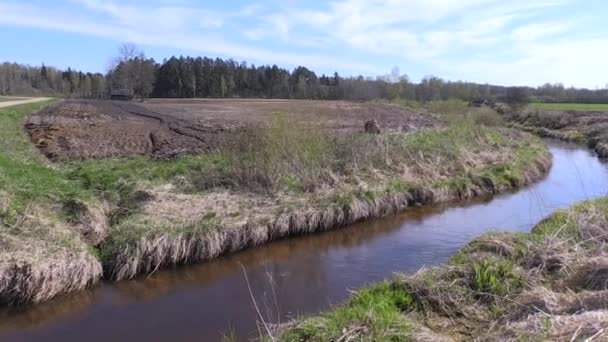 Rivierwater stroom in de buurt van de landbouw geploegd veld en verlaten houten huis — Stockvideo