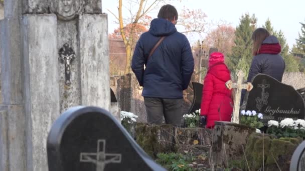 Familia joven visita el cementerio rural antiguo y grave en otoño. 4K — Vídeo de stock