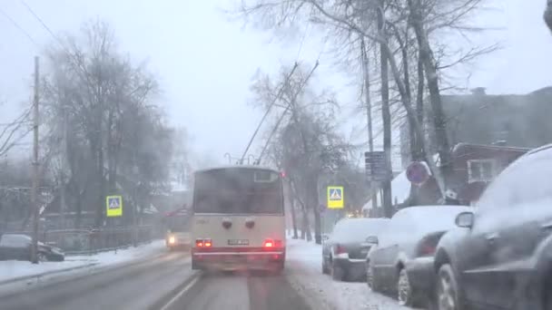 Vozový autobus, který jezdí městskou městskou ulicí ve sněhové bouři, padá v zimě. 4k — Stock video