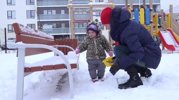 Madre jugar con la nieve del bebé en el parque infantil tiempo de invierno. 4K — Vídeo de stock