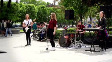 Genç kızların rock grubu sokak müziği gününde şarkı söyler ve gitar çalar..