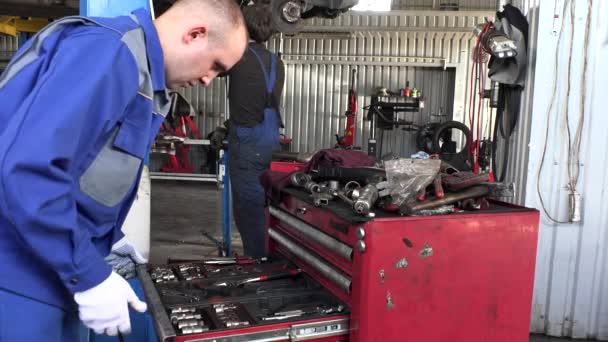 Mecánico en busca de herramientas en los cajones en el garaje de reparación . — Vídeo de stock