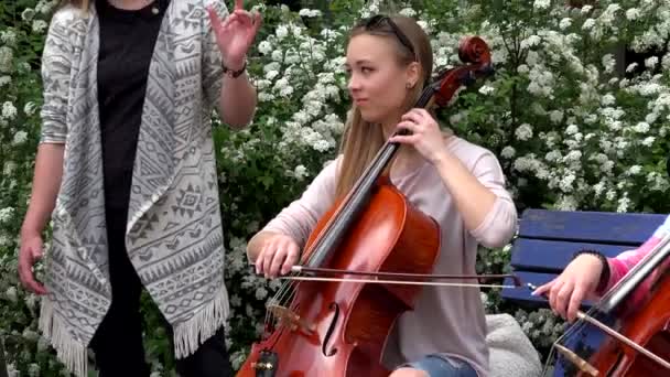 Kadın vokalist sokakta çalan müzisyen violoncellist ile şarkı. Uzaklaştırma. — Stok video