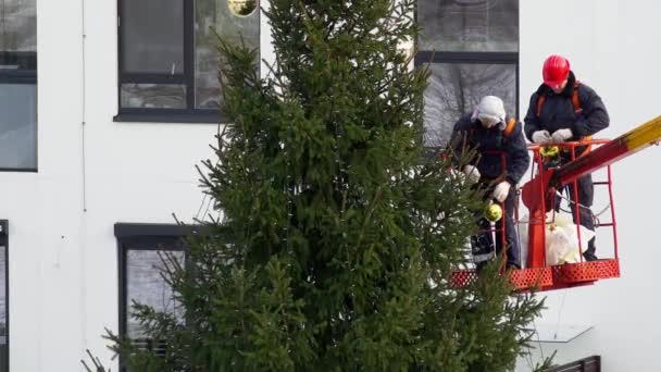 Män dekorera julgran på hög kran i Flat House District — Stockvideo