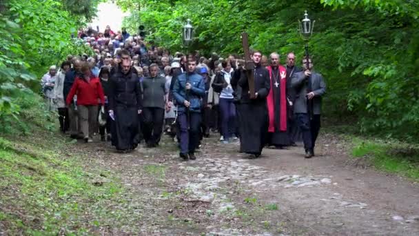 Prozession religiöser Menschen mit Kreuz durch den Waldweg. Kalvarienweg — Stockvideo