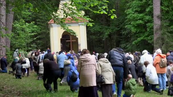 Religiösa människor knäböjer och ber framför trä korsets nära kapell — Stockvideo