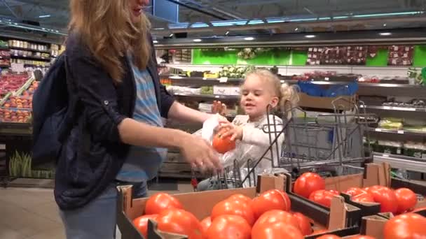 Zwangere moeder met mooie dochter plukken tomaten fruit in de supermarkt — Stockvideo