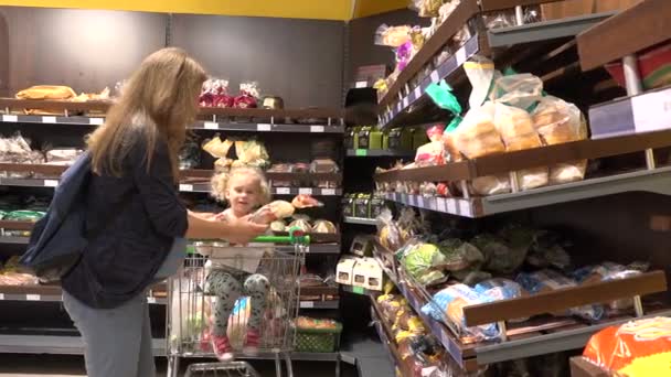 Zwangere vrouw met schattig meisje dochter in kar winkelen brood in de supermarkt — Stockvideo