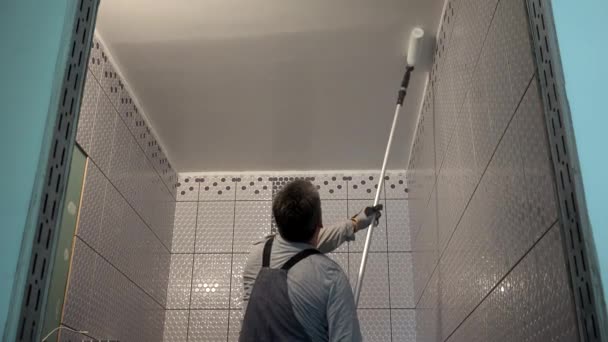 带滚子工具的工人油漆浴室天花板 — 图库视频影像