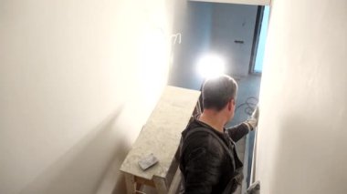 amatör adam duvar öğütür. Handyman duvarları zımpara kağıdıyla hizalar. El