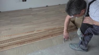 Spatulalı adam beton zeminüzerine ahşap yapıştırıcı uygular
