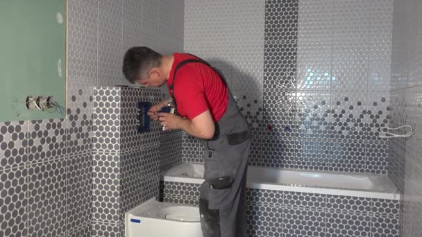 Сантехник монтирует туалетную воду, смывая кнопку в новой ванной комнате квартиры — стоковое видео