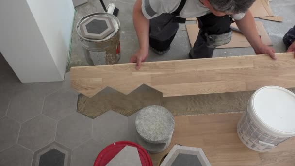 Travailleurs professionnels hommes poser panneau de plancher en chêne près de carreaux hexagonaux — Video