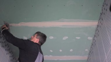 İşçi alçı taşı alçı tahtası çerçevesini alçı macunu ile onarıyor