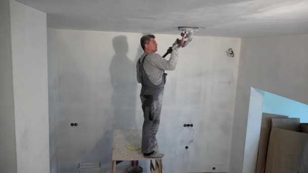 Dirty plasterer man polish ceiling with sanding grinder machine — Stock Video