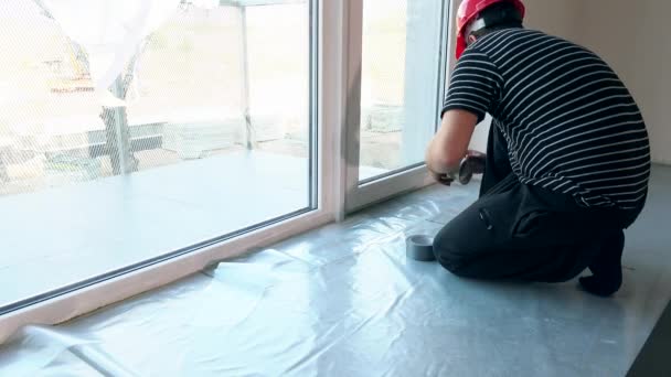 Чоловік працівник поклав поліетиленову плівку на підлогу — стокове відео