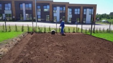 Profesyonel işçi adam düz bahçe toprak için çim rulo çeker. Gimbal hareketi