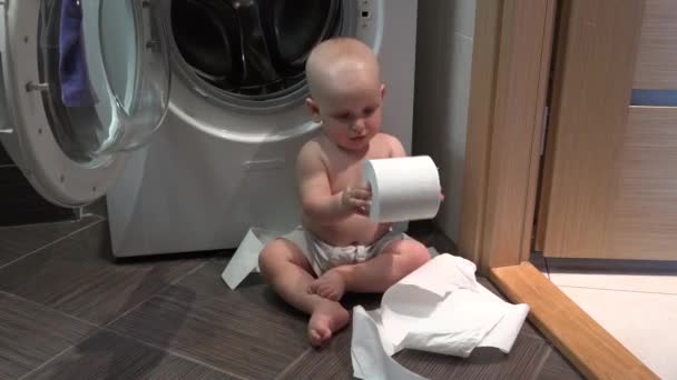 Kaukasische kind jongen spelen met wc-papierrollen in de badkamer — Stockvideo