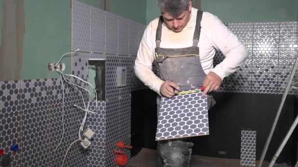 Hombre con herramienta medidor y marcador medir baldosas y hacer marcas en baldosas de cerámica de pared — Vídeos de Stock