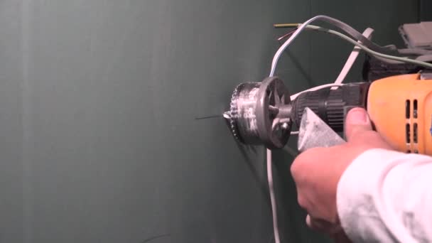 Hands with drill and crown drilling round hole in drywall plasterboard — Stock Video