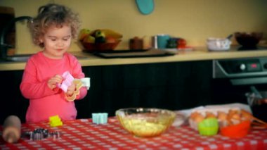 Komik çocuk renkli çerez formları ile oynuyor. Kız o meraklı görünüyor.