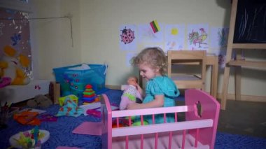 Bebek bebek ve oyuncak yatak ile oynayan Lovely küçük sarışın bebek bebek