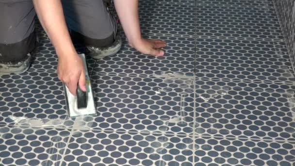 Manos de trabajador de tiler llenando huecos entre azulejos con una lechada — Vídeo de stock