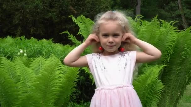 Portrait of little cute girl with sweet cherry berries as earrings on ears. — Stock Video