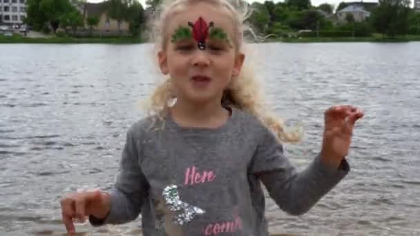 Pěkná blonďatá holka před kamerou u jezera. Gimbalové pohyby — Stock video