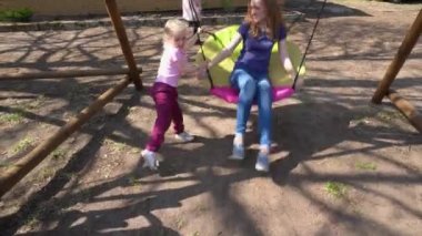 Sevimli sarışın kız çocuk yuvarlak açık salıncak onu anne salıncak. Gimbal hareketi