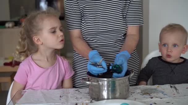 Fratello e sorella guardando la madre prendono uova di Pasqua dipinte dalla pentola. Gimbal — Video Stock