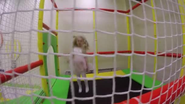 Непослушная девочка прыгает на крытом батуте в детском игровом центре — стоковое видео