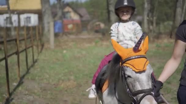 Felice ragazza carina mano onda bambino mentre cavalcare cavallo pony unicorno. Movimento di Gimbal — Video Stock