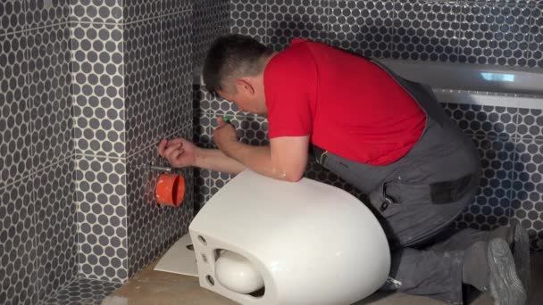 Loodgieter man bereiden voor opknoping toilet Bowl pan in nieuwe moderne badkamer — Stockvideo