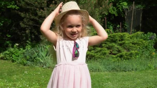 Menina loira brincalhão jogar fora chapéu. Menina feliz com vestido rosa. Movimento de Gimbal — Vídeo de Stock